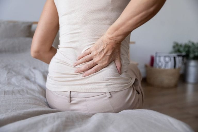 A women with back pain after sleeping on a mattress with the springs poking thru