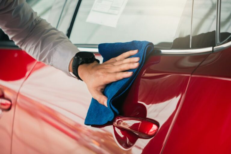 Man Wiping Down Door of Red Car With Rag