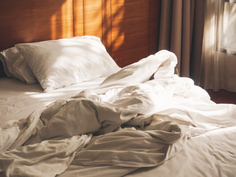 Sunlight Streaming Through Window on to Unmade Bed