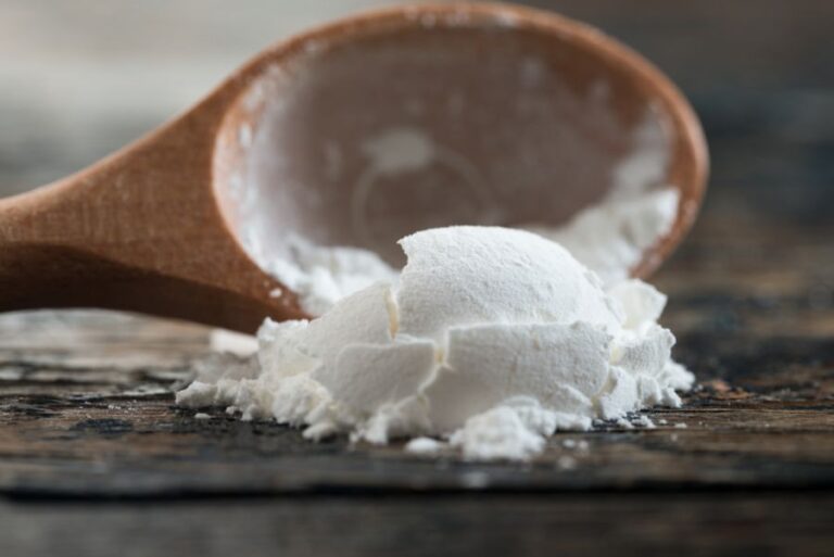 Corn Starch Spilling Out of a Wooden Teaspoon Measurement