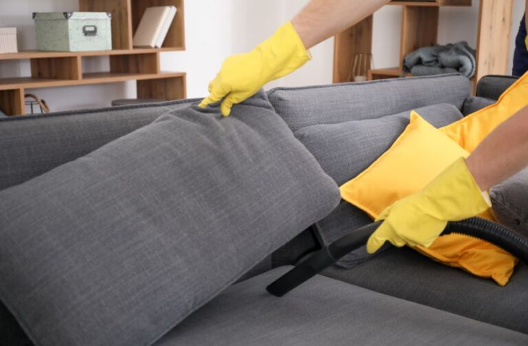 Vacuuming Under a Couch Cushion While Wearing Rubber Gloves