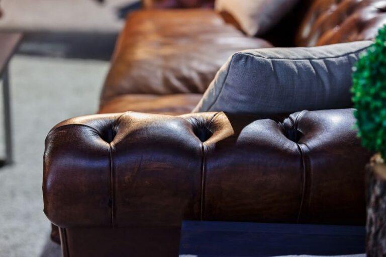 Arm of Leather Couch Accented With Gray Pillow