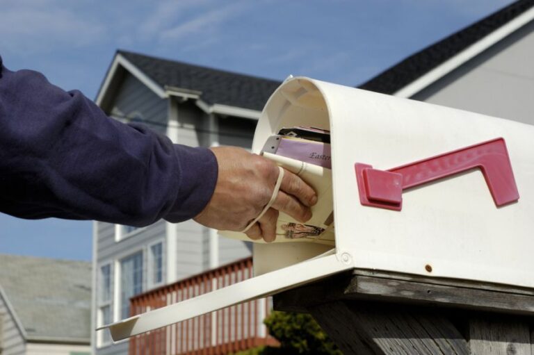 Mail Being Put Into an Open White Mailbox