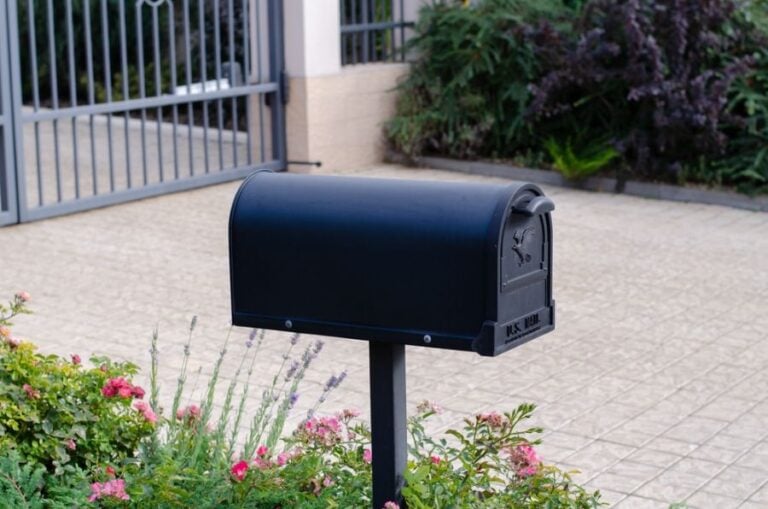 Nice Black Mailbox Surrounded by Flowers Next to a Brick Driveway