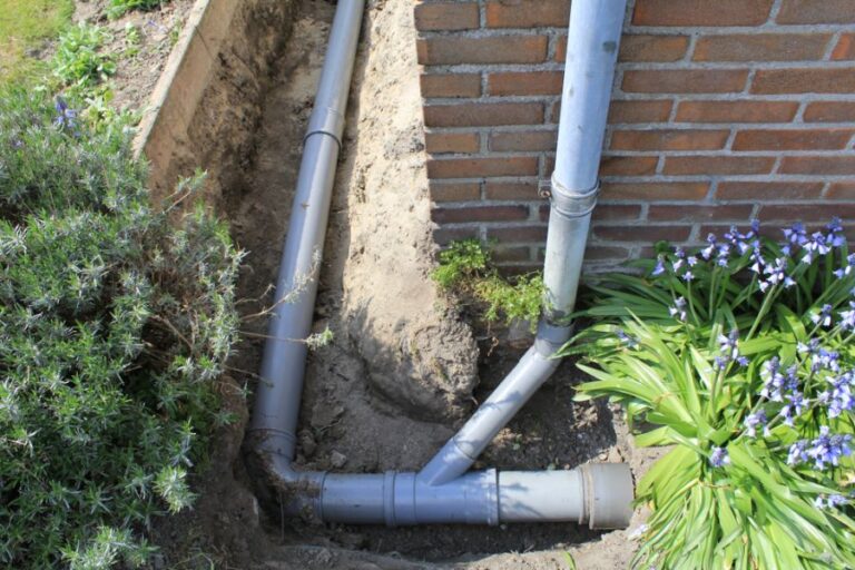 Gray Plastic Pipes Extending the Downspout Buried in the Ground