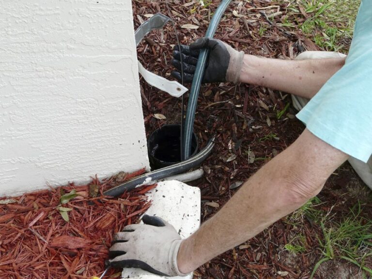 Homeowner Using Sewer Snake to Clear Out Underground Drainage Pipe
