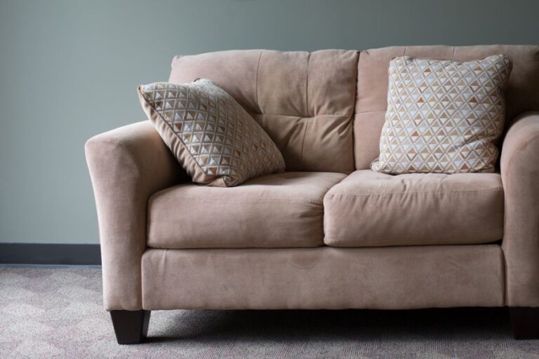 Small Tan Couch Against Blue Wall
