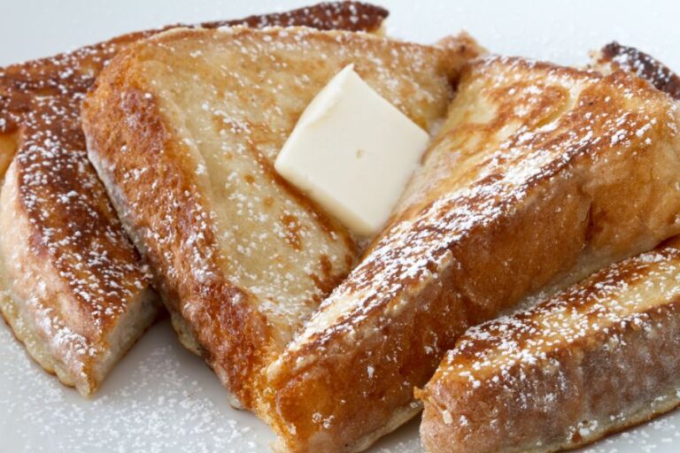 Two Cut Pieces of French Toast With Butter and Powdered Sugar