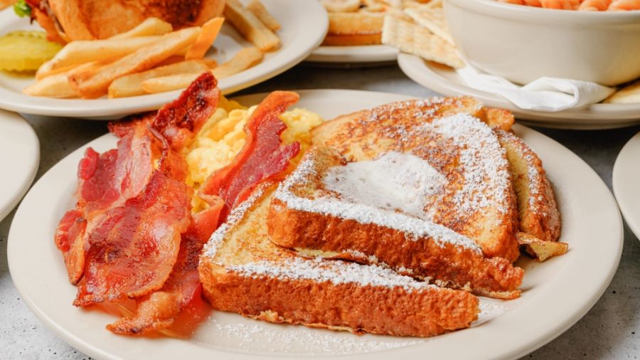 French Toast With Powdered Sugar Served With Scrambled Eggs and Bacon
