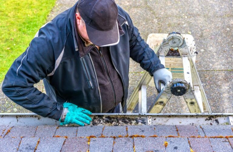 Man on a Ladder Cleaning Dirt and Leaves From a Gutter