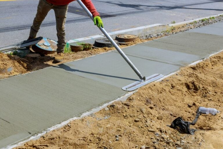 Worker Smoothing Out the Cement on a New Sidewalk
